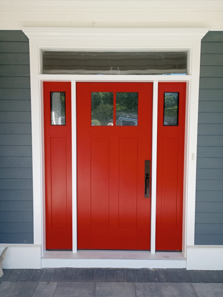 A vibrant, freshly painted solid red front door with matching red sidelights, framed by crisp white exterior architectural trim moldings, crown header, and dark slate gray horizontal lap siding, completed by Perfection Plus Painting in Mahwah, New Jersey.